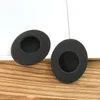 Two black foam ear pads are placed on a wooden surface with a white background. Voir les images du produit