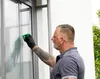 A man is cleaning a window with a cleaning kit. Podgląd zdjęcia produktu