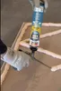 A person wearing gloves is using a Soudal SoudaBond Turbo construction adhesive dispenser to apply foam to a surface. Produktbild-Vorschau