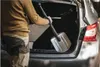 A person is putting a shovel into the trunk of a car. Náhled obrázku produktu