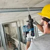 A construction worker is drilling into a concrete ceiling with a Bosch cordless rotary hammer drill. Produktbild-Vorschau