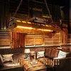 A dimly lit room with a hanging lamp, sofas, and wooden accents. Produktbild-Vorschau