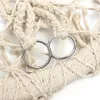 A close-up of a cream-colored macrame hammock chair with two silver metal rings. Produktbild-Vorschau