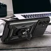 A black phone case with a ring holder is placed on a wooden surface next to a laptop and headphones. Náhľad obrázku produktu