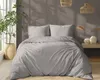A bedroom scene with a bed made up with beige striped bedding, a large potted plant, and woven pendant lights. Anteprima dell’immagine prodotto