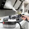 A hand is using a steam cleaner to clean a kitchen range hood above a stovetop. Náhled obrázku produktu