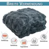 A folded dark gray plush blanket is shown, with icons and text below illustrating its various uses. Produktbild-Vorschau