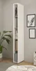 A tall, narrow white shelf unit with wooden shelves, displaying books and decorative items, placed in a room with a plant and framed artwork on the wall. Produktbild-Vorschau