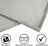 Close-up of a gray blanket with three icons and text below them indicating product features. Produktbild-Vorschau