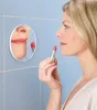 A woman applying lipstick in front of a mirror. Náhľad obrázku produktu