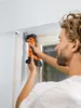 A man is using a cordless oscillating multi-tool to cut or sand near a window frame. Náhľad obrázku produktu