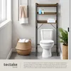A bathroom scene featuring a toilet, a shelving unit, a basket of towels, and a towel rack. Náhled obrázku produktu