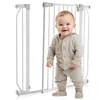 A baby stands in front of a white baby gate. Voir les images du produit