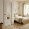 A bedroom with a bed, a window, and a door with a mirror hanging on it. Anteprima dell’immagine prodotto