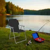 A camping chair and fishing gear are set up by a lake. Produktbild-Vorschau