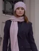 A woman wearing a pink beanie and scarf over a black coat. Produktbild-Vorschau