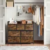 A dresser with drawers in a closet setting, with clothes hanging on a rack. Náhled obrázku produktu