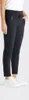 A person wearing black pants and white sneakers, shown from the side. Produktbild-Vorschau