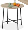 A round dining table with a wooden top and black metal legs, set with a green mug, a green plate, and a bottle of orange juice with two apples. Náhled obrázku produktu