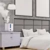 A humidifier is shown on a nightstand next to a bed in a bedroom. Produktbild-Vorschau