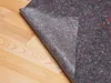 A piece of gray felt material is partially unrolled on a light brown wooden floor. Produktbild-Vorschau