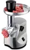 A stainless steel meat grinder with a black lid and a tray filled with cubed meat, with ground meat exiting the grinder. Podgląd zdjęcia produktu