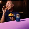 A man is eating french fries next to a spice jar. Produktbild-Vorschau