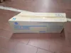 A cardboard box containing a printer part is placed on a tiled floor. Anteprima dell’immagine prodotto