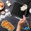 A person is pouring waffle batter into a waffle maker, with ingredients like eggs, butter, and flour scattered around. Náhľad obrázku produktu