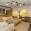 A living room with a sectional sofa, coffee table, and chairs, illuminated by a track light fixture. Voir les images du produit