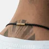 Close-up of a person's neck wearing a black braided leather necklace with a gold clasp. Produktbild-Vorschau
