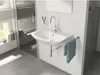A modern bathroom sink with a faucet running water, a towel hanging on a rack, and a window with books on the sill. Anteprima dell’immagine prodotto