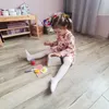 A young girl is playing with a toy toaster and breakfast accessories on the floor. Anteprima dell’immagine prodotto