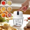 A hand presses a button on a mini electric chopper, surrounded by small bowls of chopped ingredients and whole garlic and chili peppers. Produktbild-Vorschau