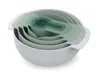 A set of nesting mixing bowls and measuring cups in various shades of green and gray, stacked together. Produktbild-Vorschau