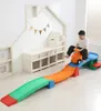 A child is riding a toy car down a colorful slide in a playroom. Voir les images du produit