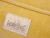 A close-up of a yellow dog bed with a brand tag. Produktbild-Vorschau
