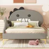 A child's bed with a dinosaur-shaped headboard, decorated with pillows and a blanket, in a bedroom setting. Produktbild-Vorschau