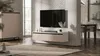 A modern living room with a TV mounted on a textured wall, a floating media console, and a dining area in the background. Produktbild-Vorschau