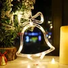 A close-up of a Christmas bell-shaped LED light decoration hanging near a decorated Christmas tree and a lit candle. Produktbild-Vorschau