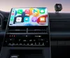 A car's dashboard with a large touchscreen displaying a smartphone interface, and a small black device mounted on the dashboard. Produktbild-Vorschau