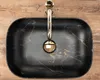 A top-down view of a black marble sink with gold accents and a gold faucet. Produktbild-Vorschau