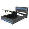 A grey upholstered bed frame with the mattress support lifted to reveal storage space underneath. Blue LED lights are visible along the base and headboard. Produktbild-Vorschau