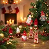 Christmas tree ornaments and decorations are displayed on a wooden surface in front of a fireplace with stockings and candles. Podgląd zdjęcia produktu