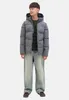 A young boy is standing and posing for a product shot, wearing a puffer jacket and jeans. Produktbild-Vorschau