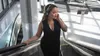 A woman wearing headphones on an escalator. Produktbild-Vorschau