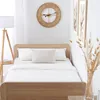 A bedroom scene with a bed, pillows, and a clock on the wall. Náhled obrázku produktu