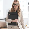 A woman in a business suit holds a black laptop sleeve. Produktbild-Vorschau