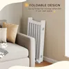 A white wooden pet gate is folded and leaning against a wall next to a sofa. The image has overlay text highlighting its foldable design. Podgląd zdjęcia produktu