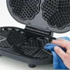 A hand is cleaning a heart-shaped waffle maker with a blue cloth. Produktbild-Vorschau